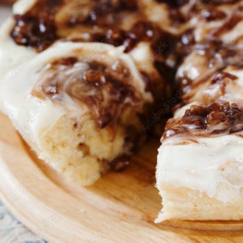 Homemade cinnamon roll apple butter in a jar with fresh apples and cinnamon sticks on wooden table background