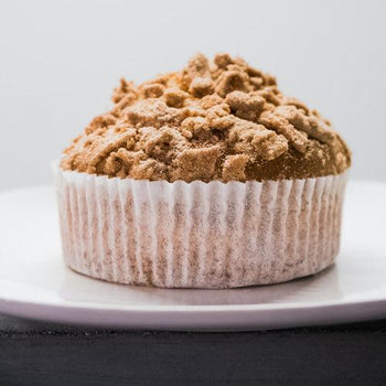 Freshly baked Good Dee's pumpkin spice muffins on a cooling rack with pumpkin puree, cinnamon sticks, and autumn spices.