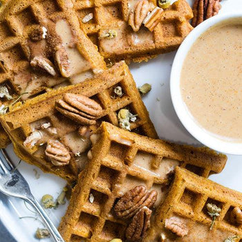 Fresh keto apple pie cinnamon waffles topped with butter, cinnamon, chopped pecans, and sugar-free syrup on a rustic breakfast table.