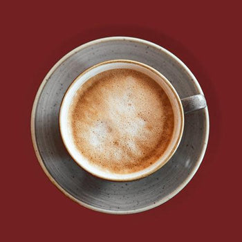 Creamy raspberry cappuccino with milk foam and berry drizzle in a ceramic coffee cup on a wooden table.