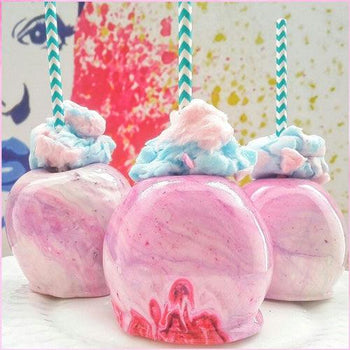 Glossy pink cotton candy apples with hard candy shell on sticks, carnival style homemade treat on parchment paper